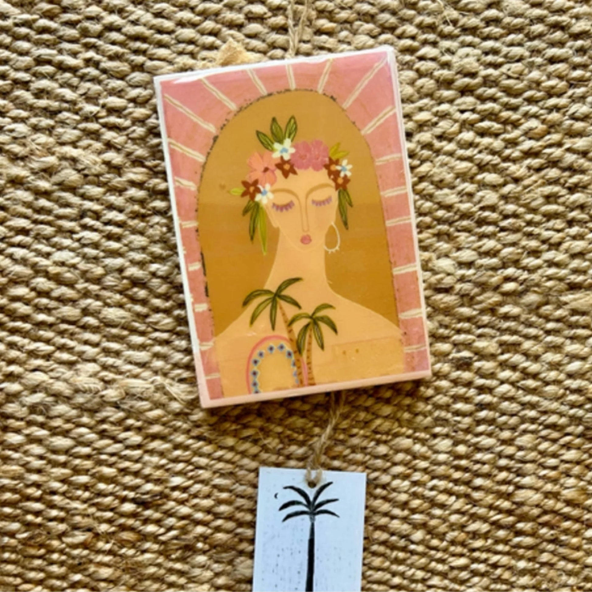 Decorative tile with a stylised illustration of a woman's face on a textured surface