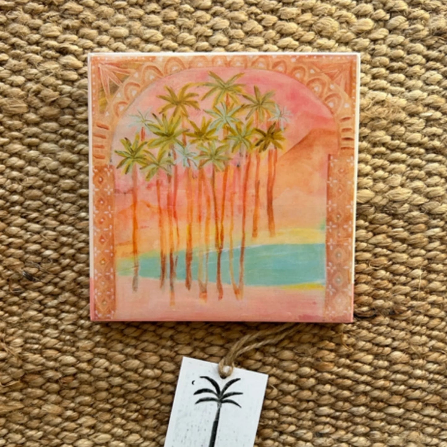 Artistic depiction of palm trees and a sun on a decorative tile.