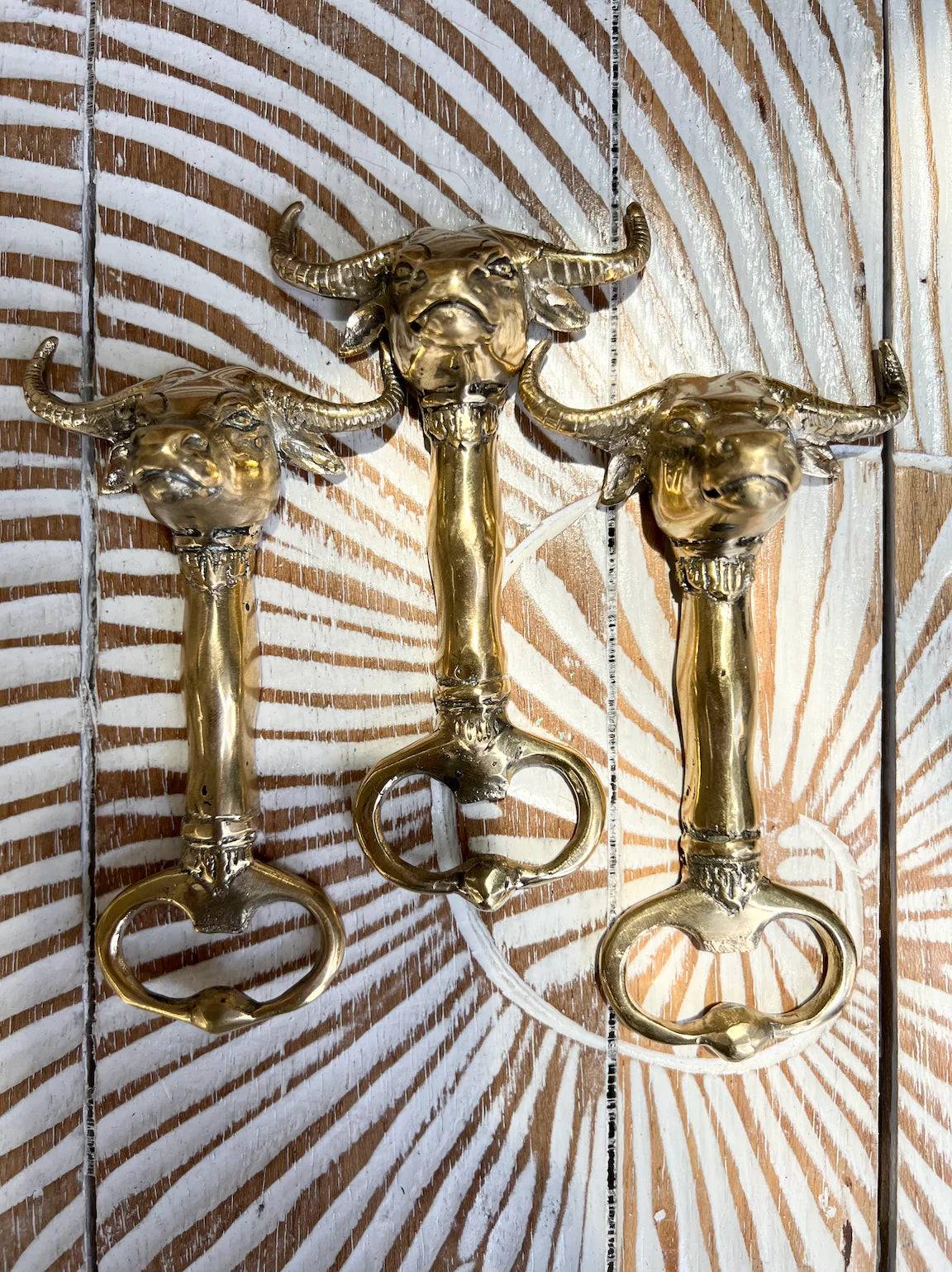 Three gold bull head bottle openers on a wooden background