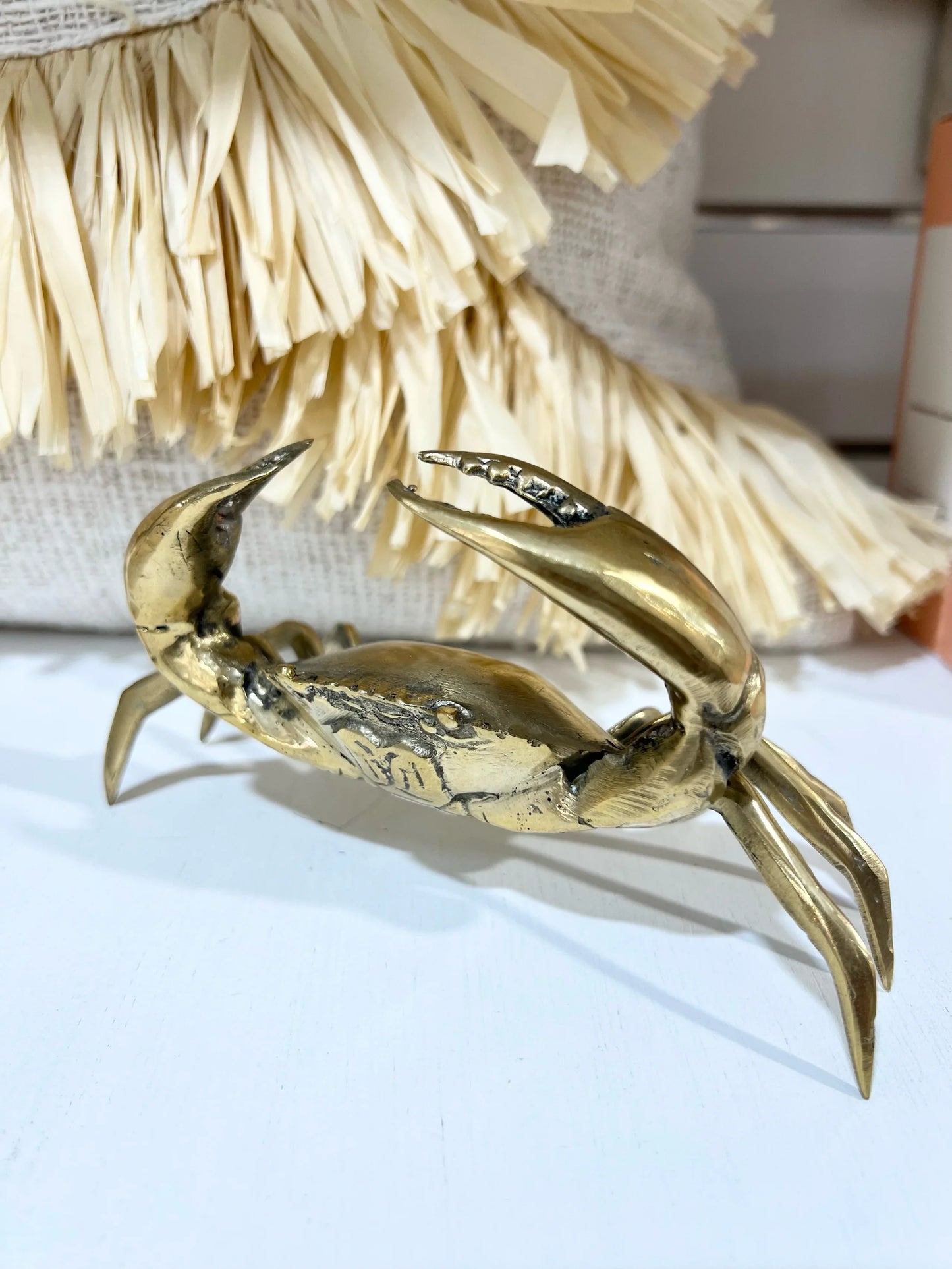 Gold crab decorative item on a white surface with a blurred background