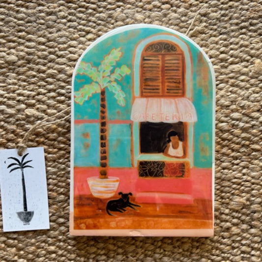 Decorative tile with a tropical design featuring a house, palm tree, and dog on a textured surface.