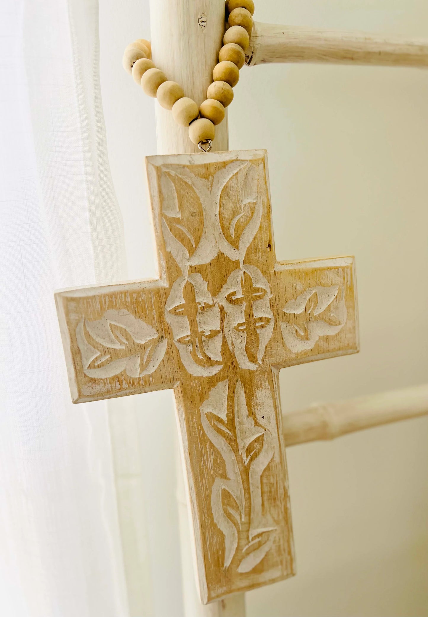 Wooden cross with engraved design on a white background