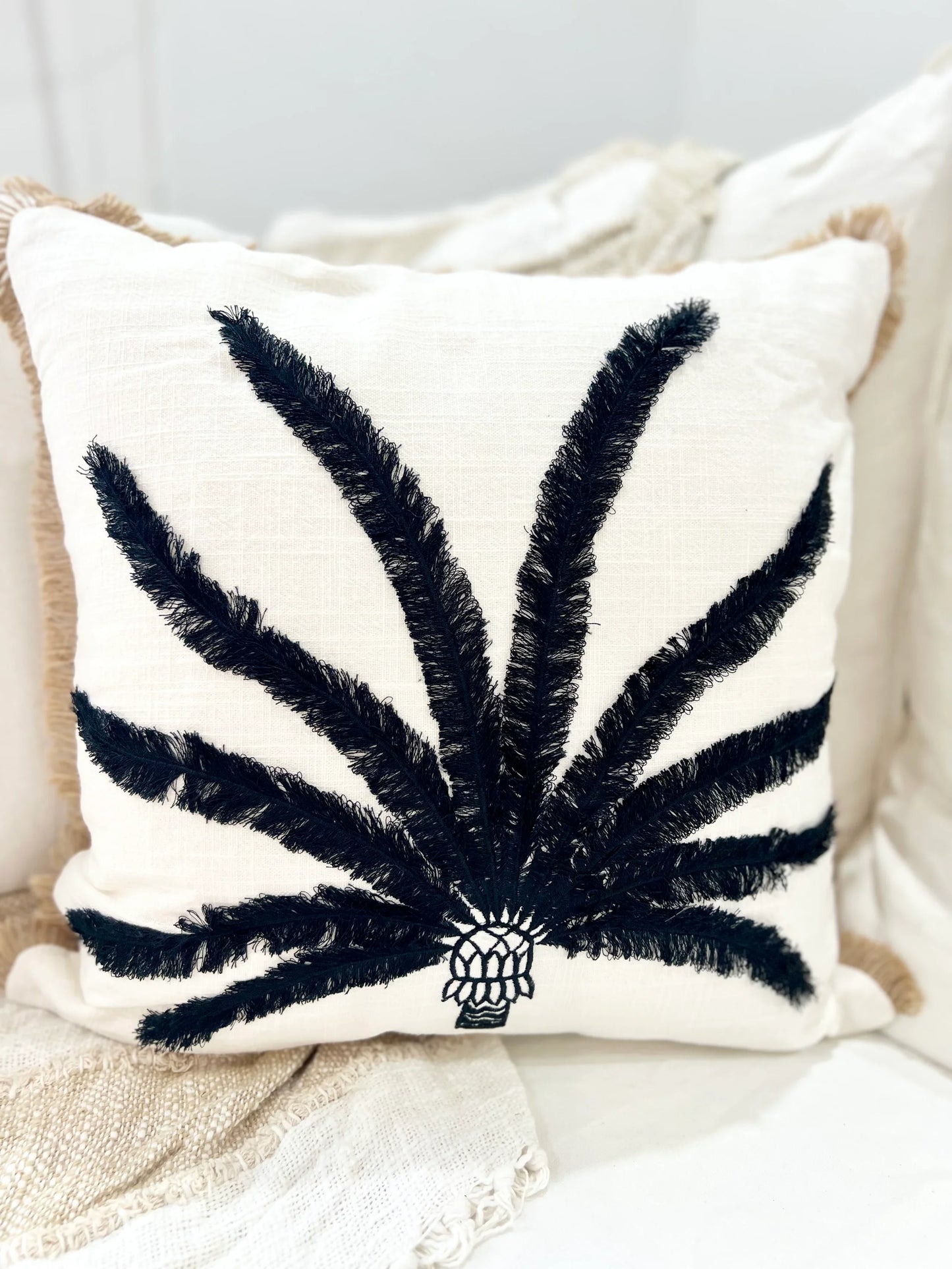 Decorative pillow with black feather-like pattern on a neutral background