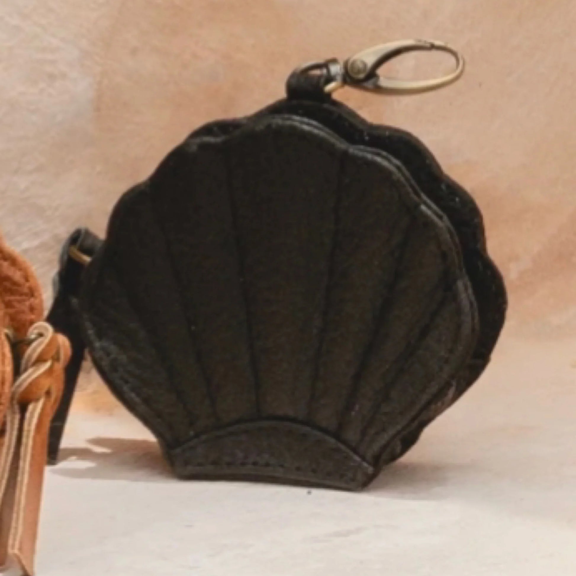 Black shell-shaped keychain purse on a beige background