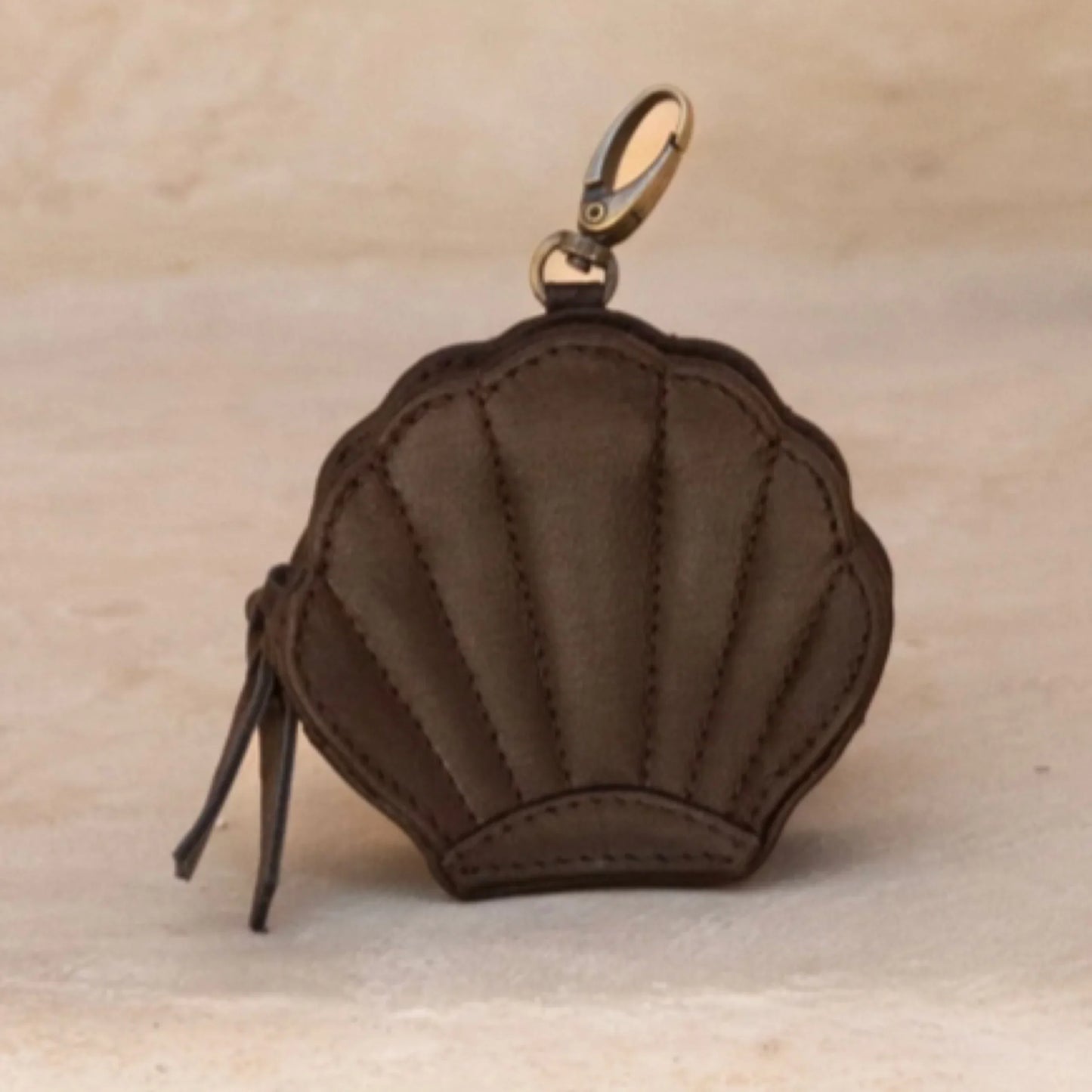 Brown shell-shaped purse with a gold clasp on a beige background