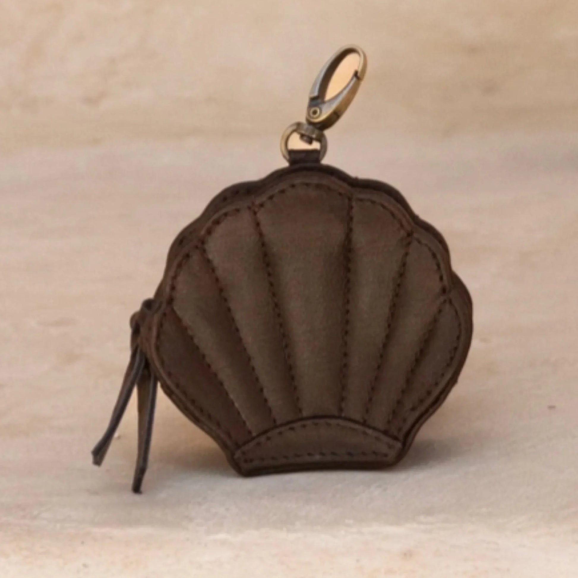 Brown shell-shaped purse with a gold clasp on a beige background