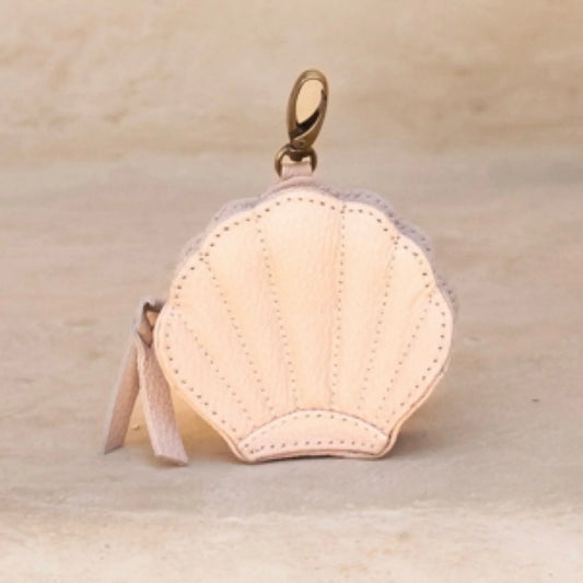 Pink leather keychain purse with a gold clasp on a beige background