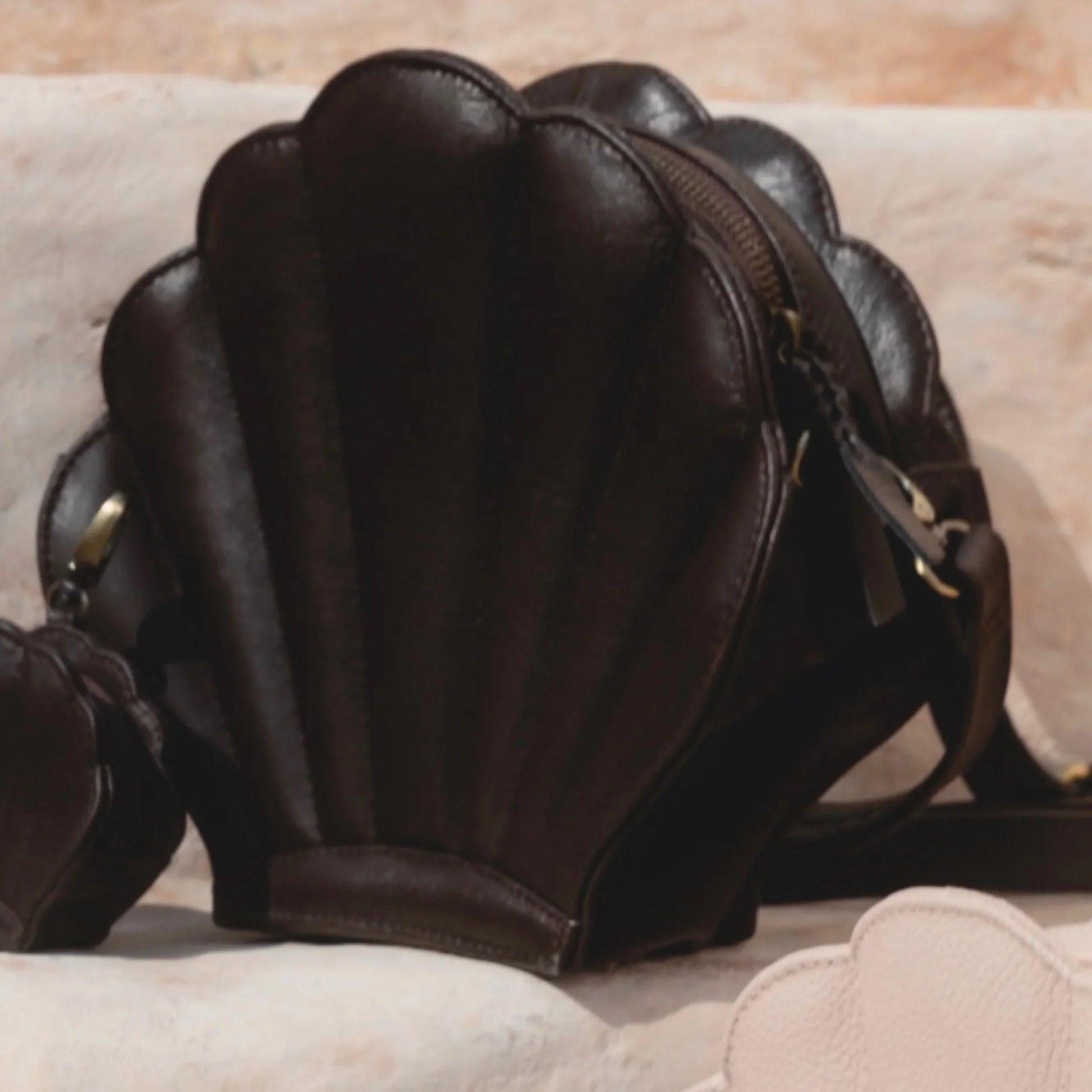 Brown leather shell-shaped handbag on a beige surface