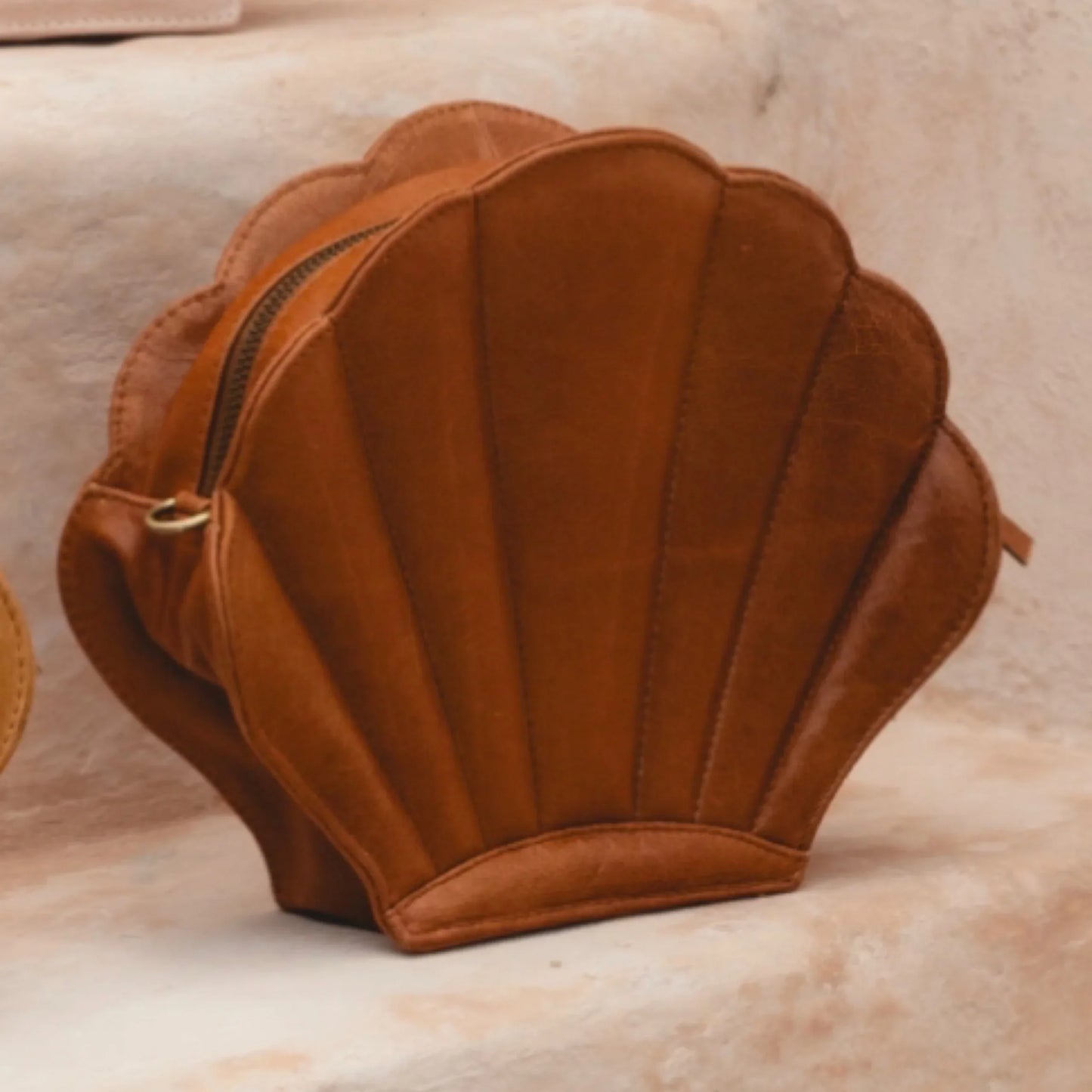 Brown shell-shaped bag on a beige surface