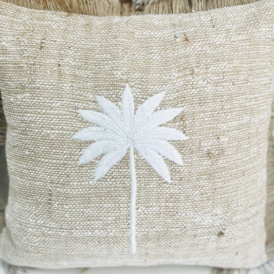 Beige pillow with white embroidered palm tree design