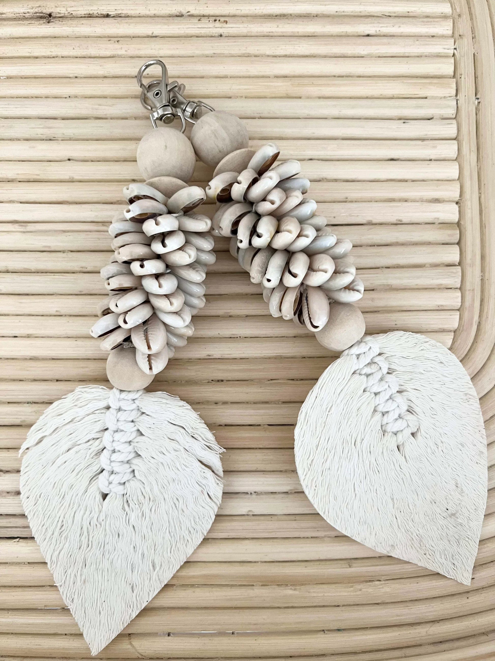 Pair of white earrings with shell-like beads on a woven background