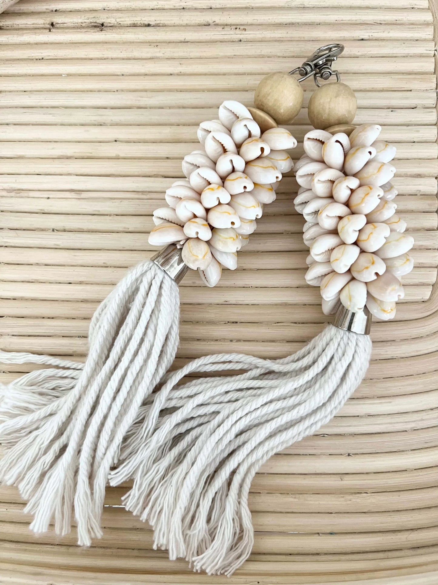 Beige and white beaded keychain with tassels on a woven background