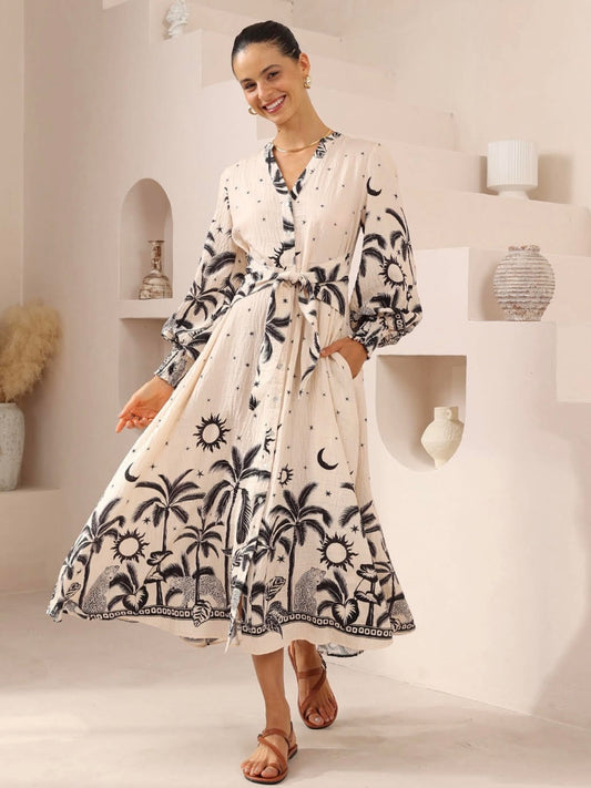 Woman wearing a white dress with black patterns in a minimalistic room.