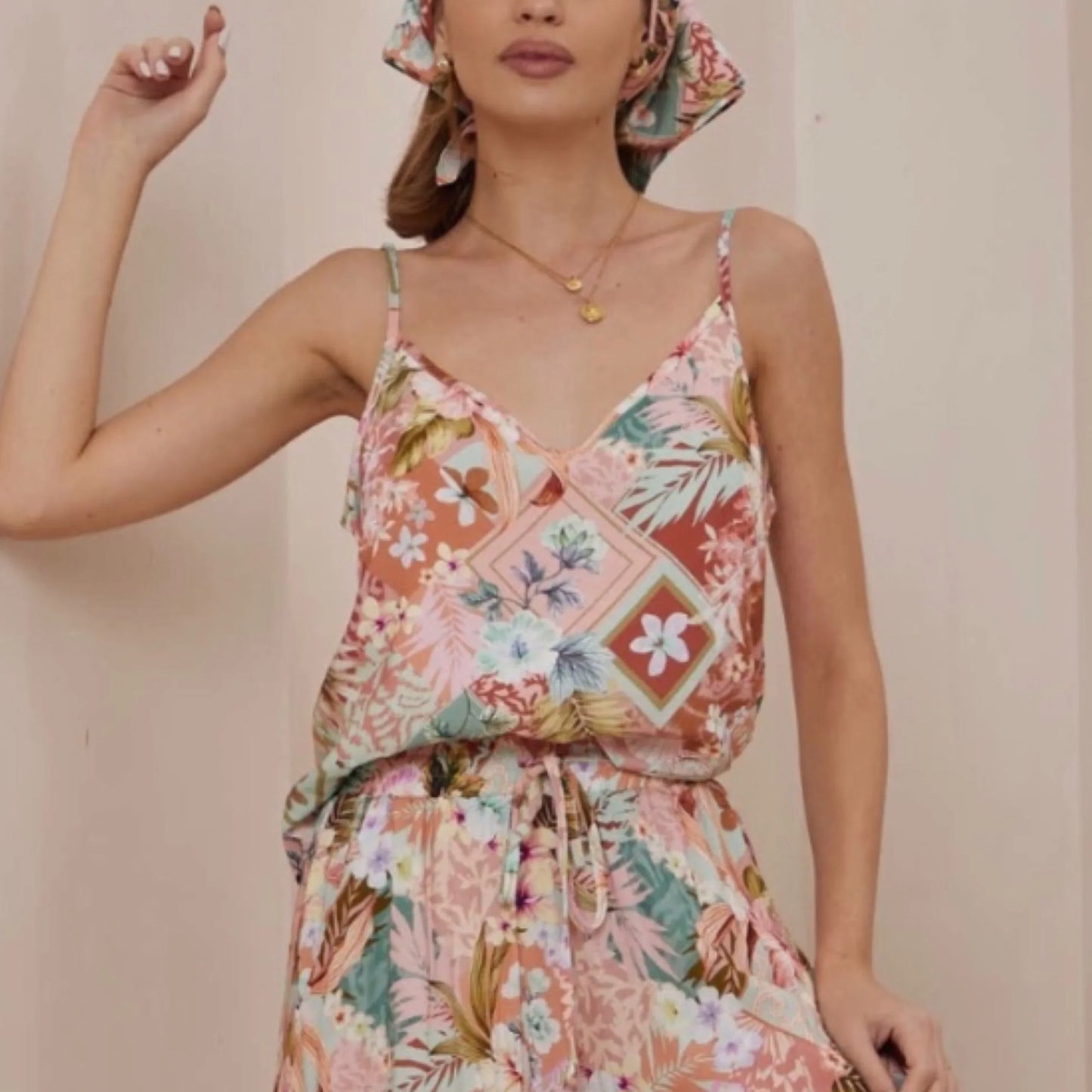 Woman wearing a colorful floral dress against a plain background