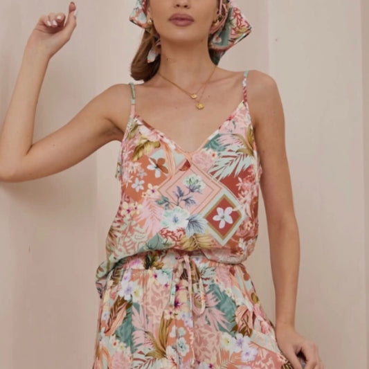 Woman wearing a colorful floral dress against a plain background
