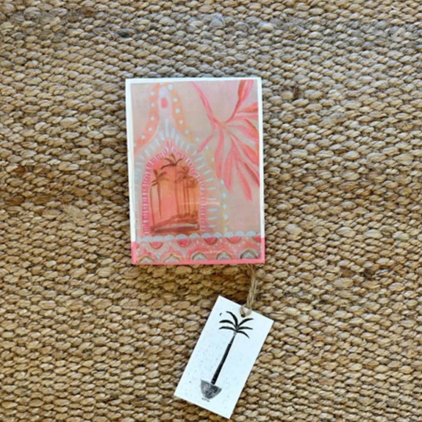 Small decorative tile with a pink design on a textured surface