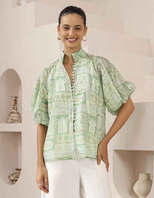 Woman wearing a green patterned blouse in a minimalistic setting