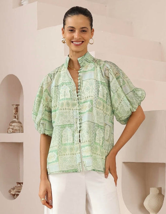Woman wearing a green patterned blouse in a minimalistic setting