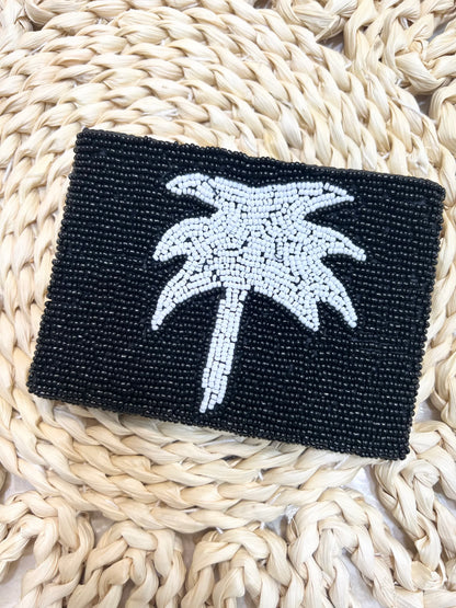 Black beaded clutch with a palm tree design on a woven surface
