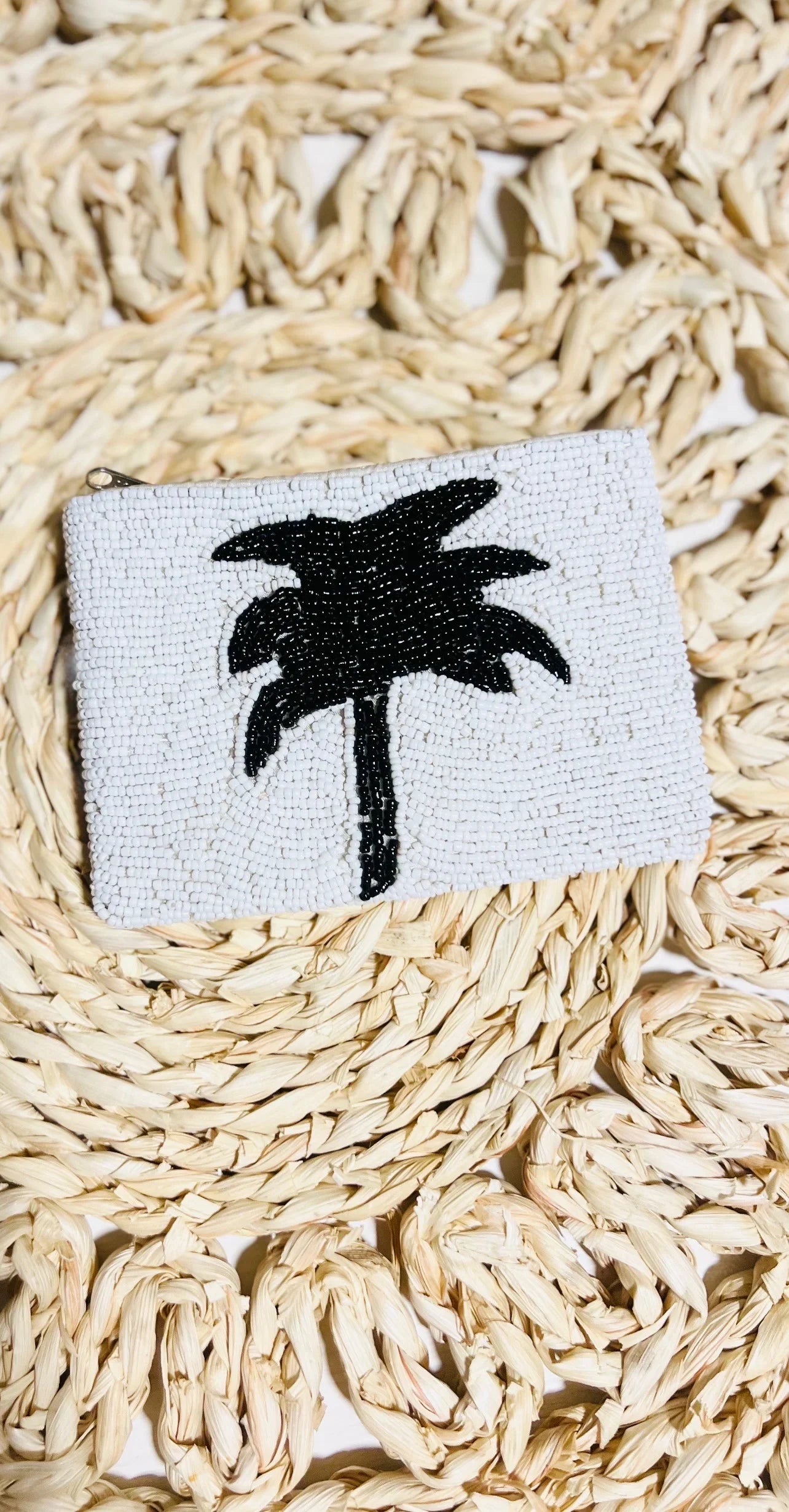 Small coin purse with a palm tree design on a woven surface