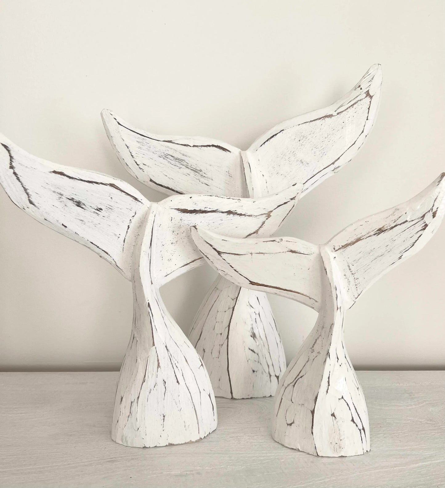 White whale tail sculptures on a neutral background