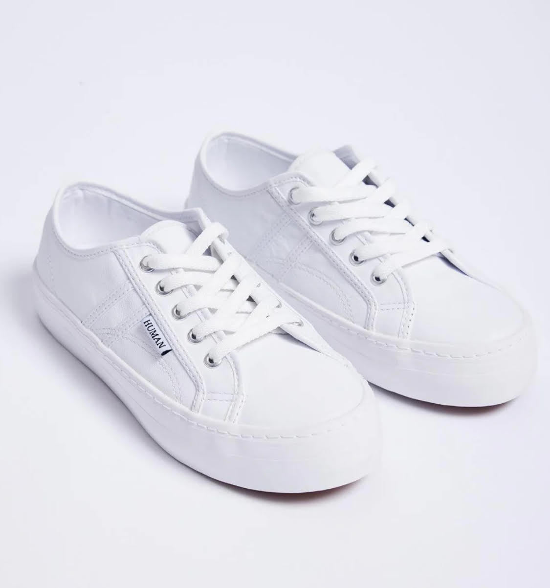 Pair of white sneakers on a light gray background