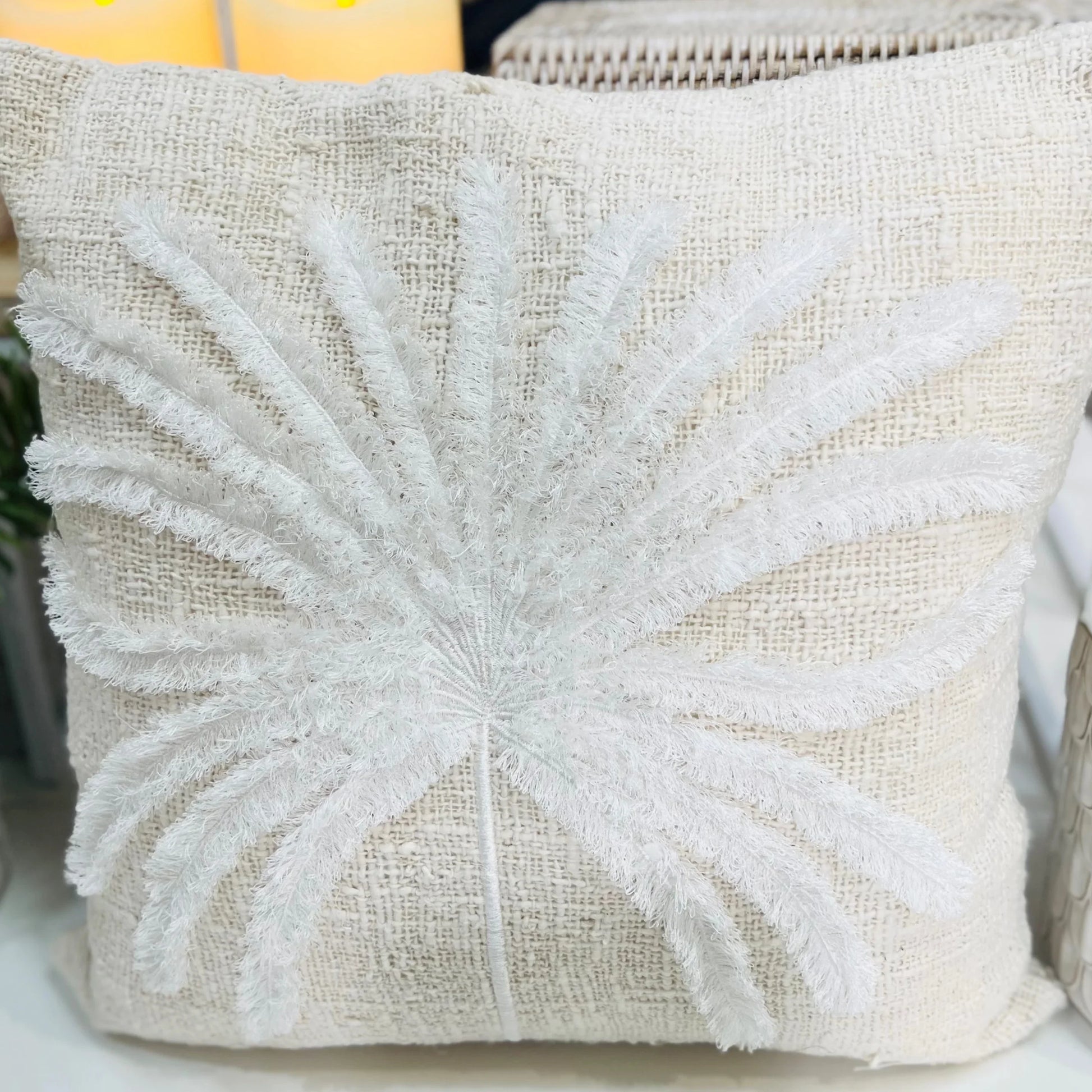 Decorative pillow with white floral embroidery on a neutral background