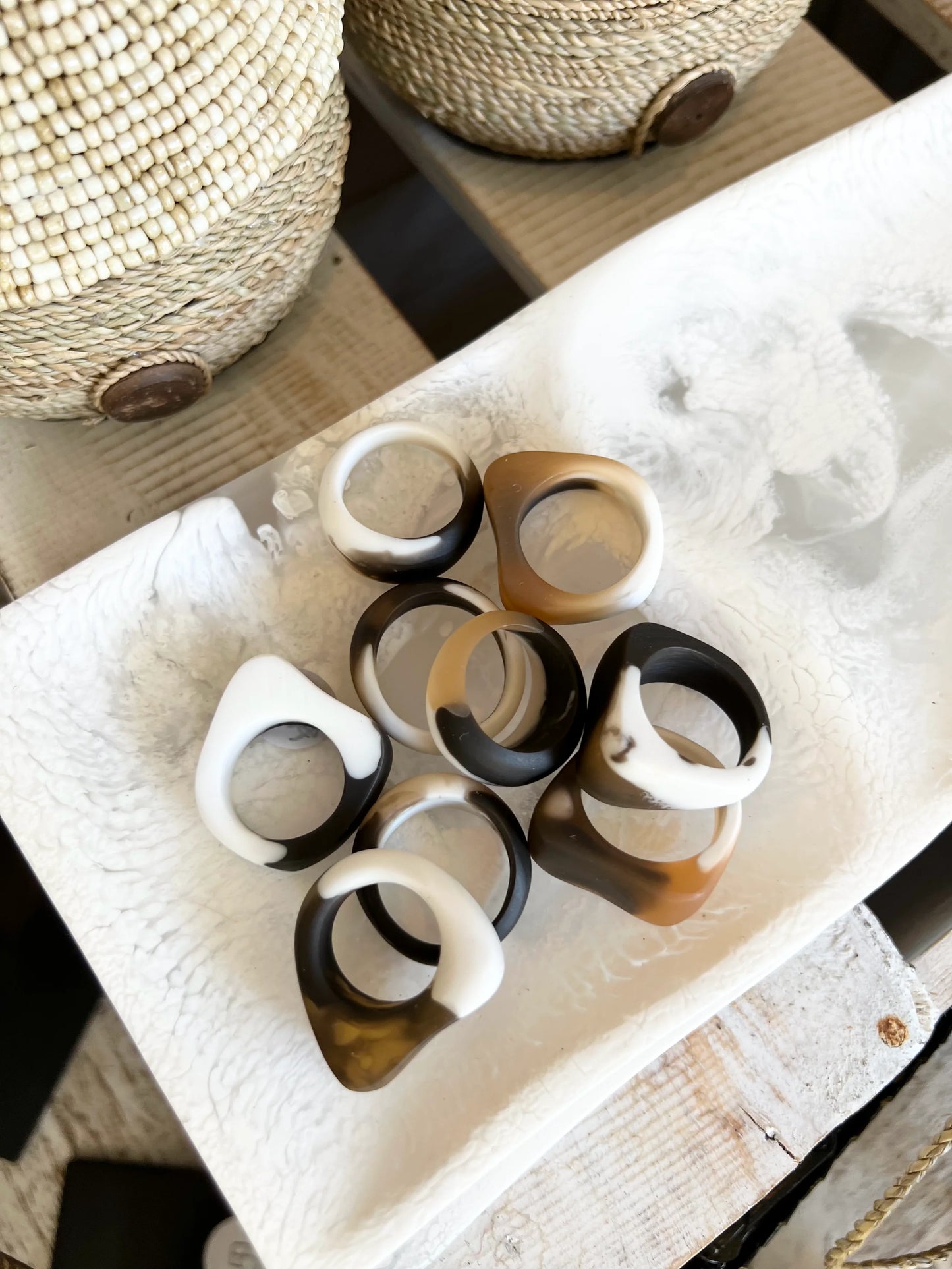 Set of resin rings on a textured surface with woven baskets in the background