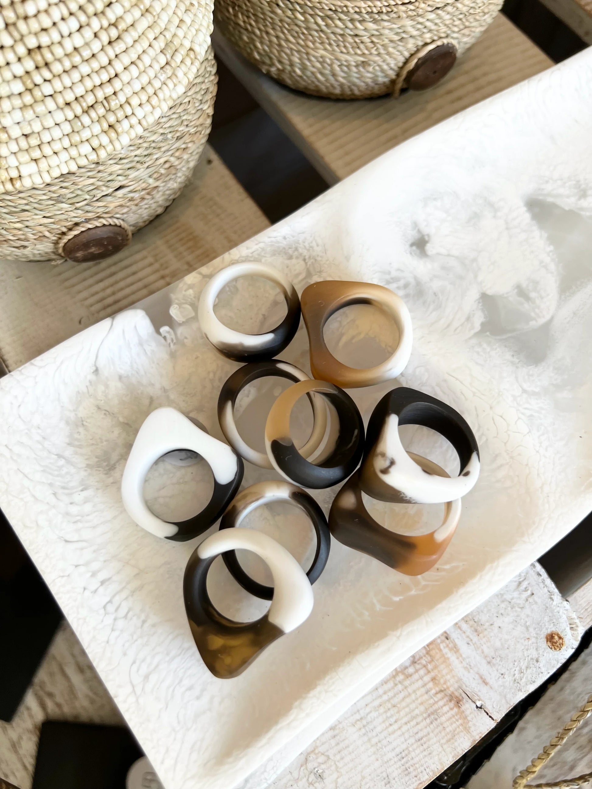 Set of resin rings on a textured surface with woven baskets in the background