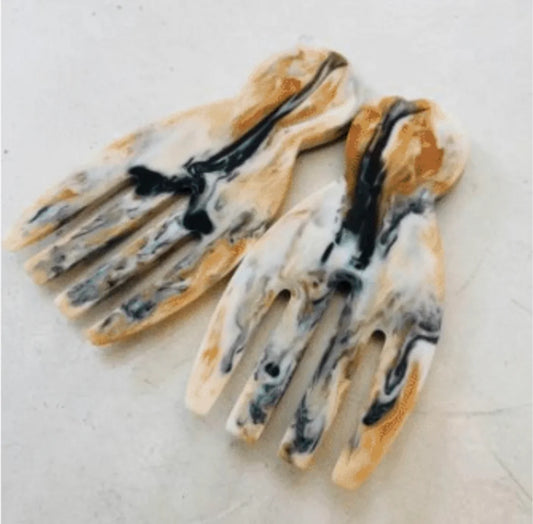 Pair of marbled resin salad tongs shaped like hands on a light surface