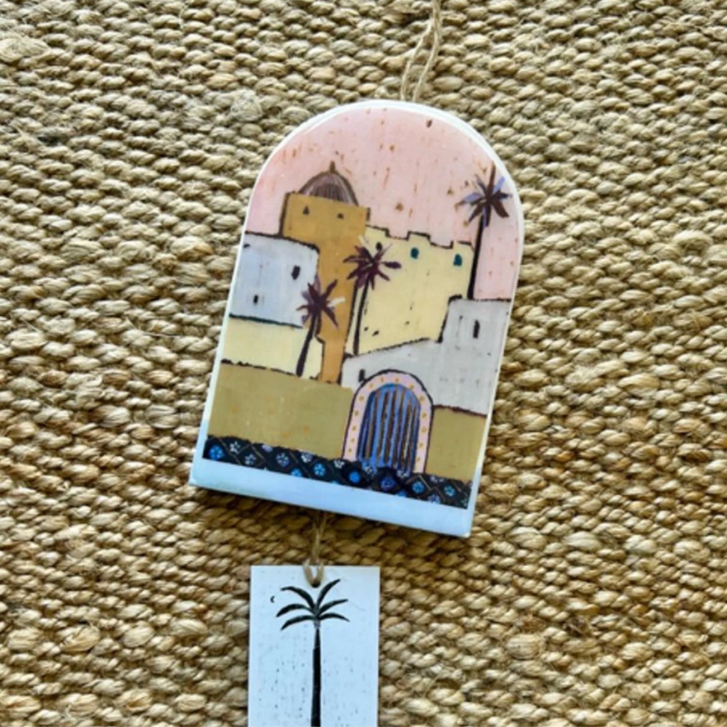 Decorative hanging ornament with a cityscape design on a textured surface