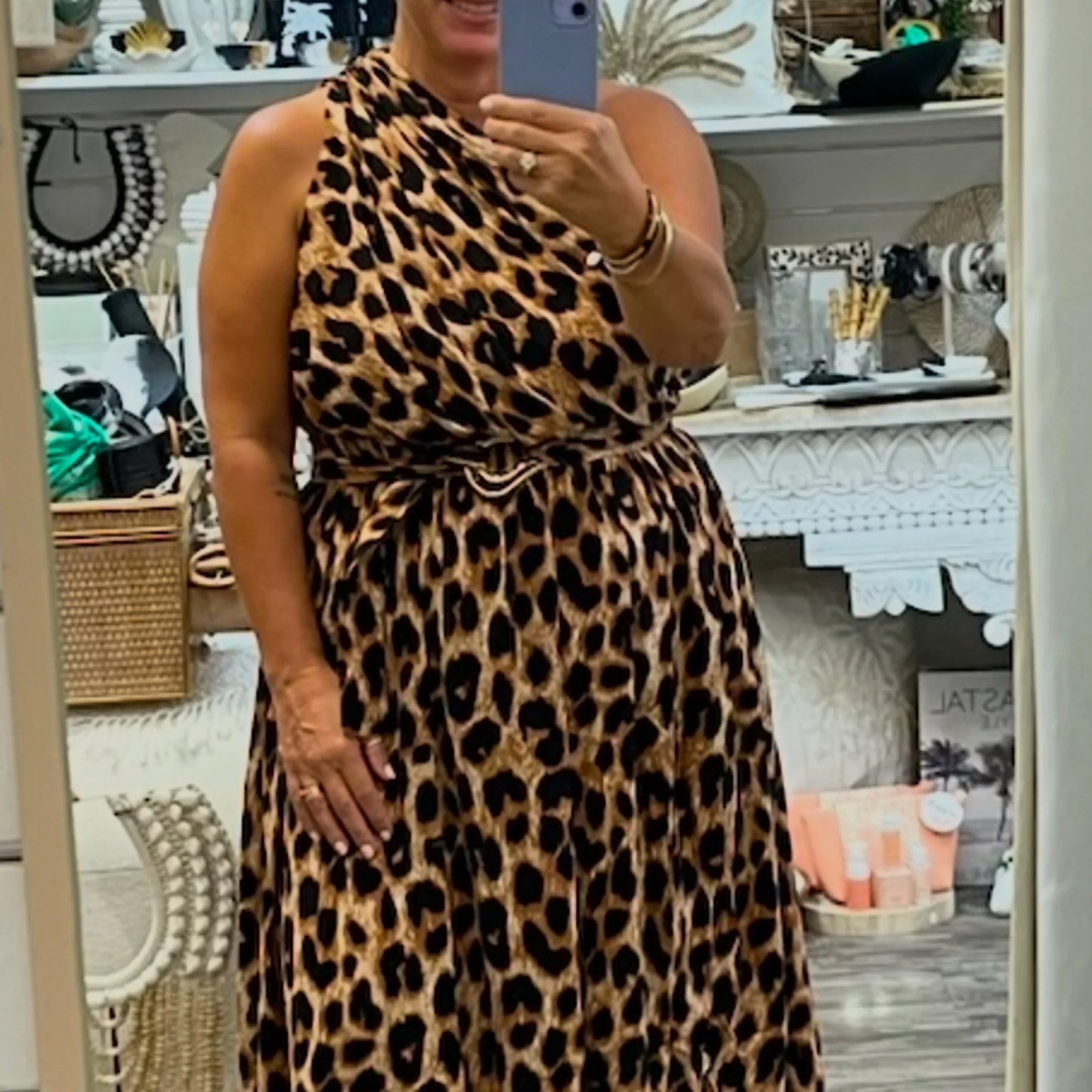 Person wearing a leopard print dress taking a mirror selfie in a store.