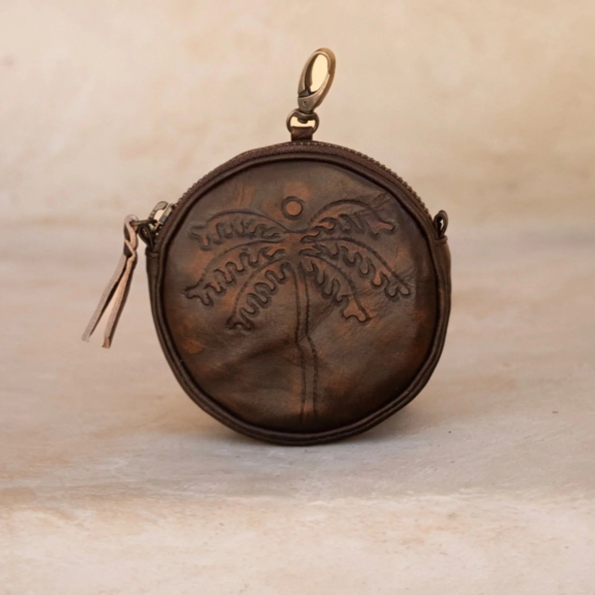 Brown leather pouch with embossed design on a beige background