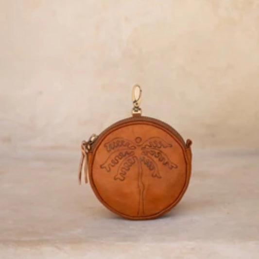 Round leather pouch with embossed design on a beige background