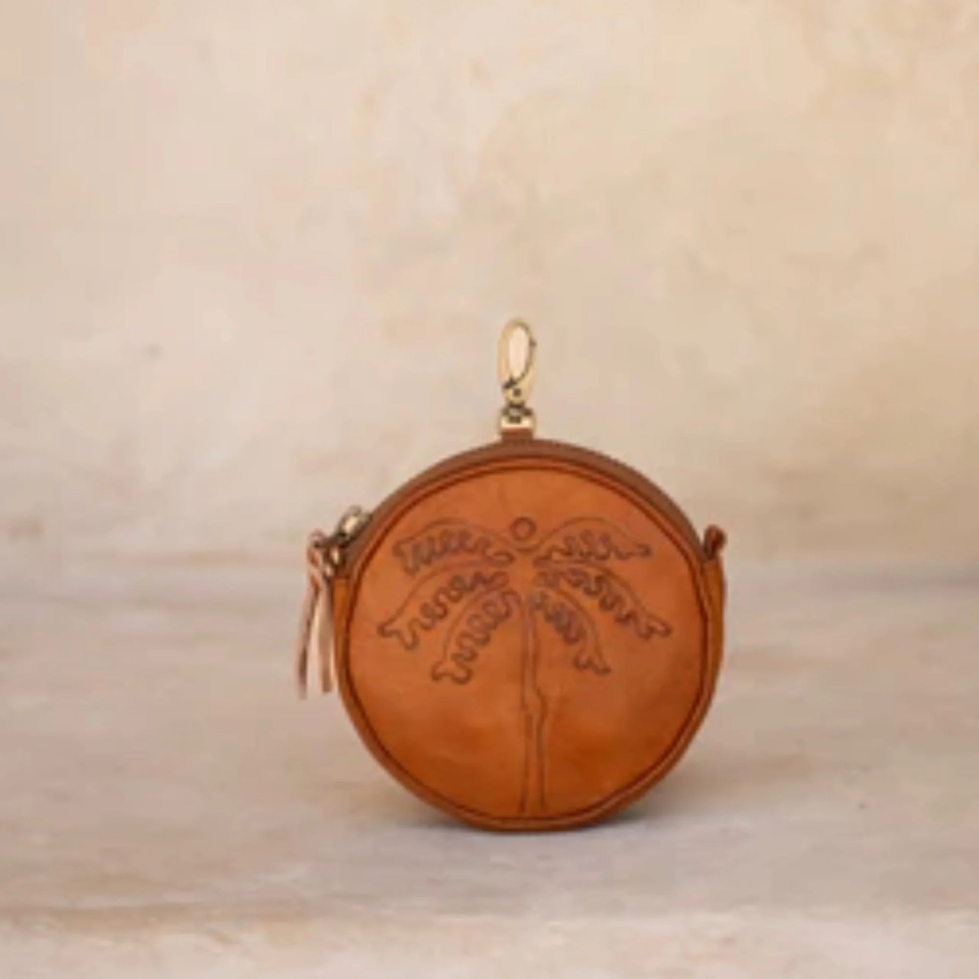Round leather pouch with embossed design on a beige background