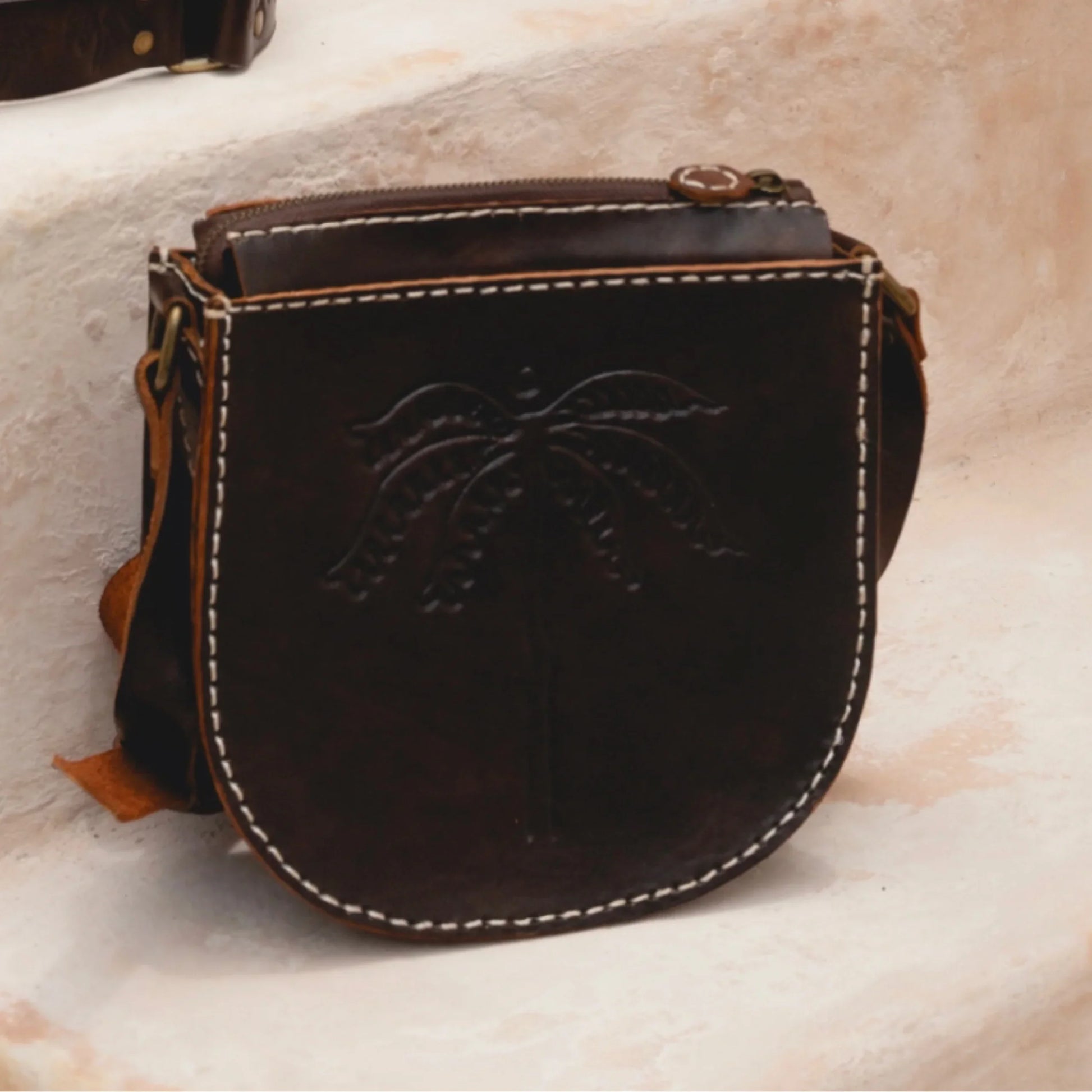 Brown leather bag with intricate design on a textured surface