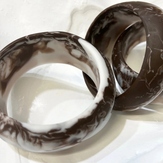 Two marbled resin brown and white bangles on a light background