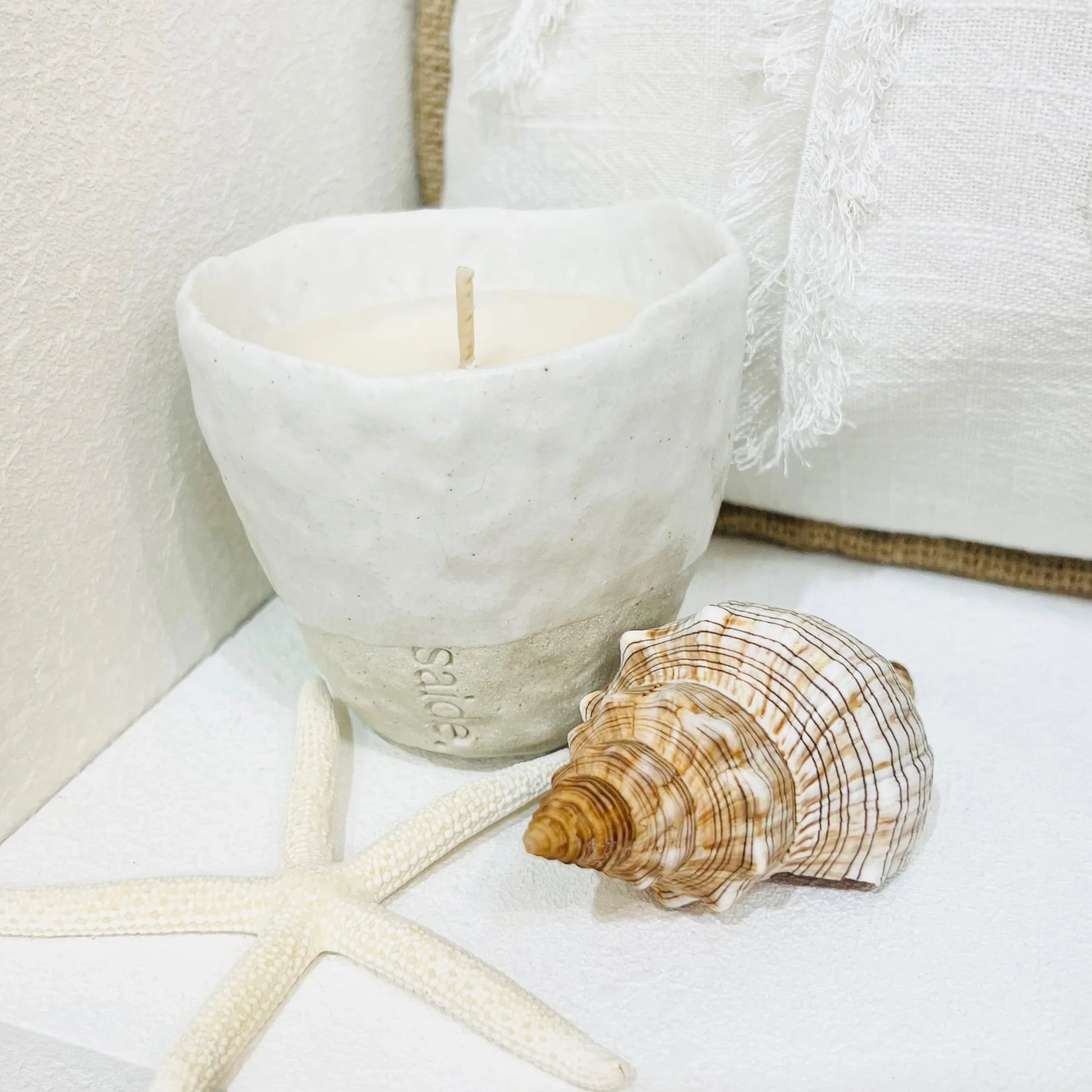 Ceramic candle with a shell and starfish on a white surface