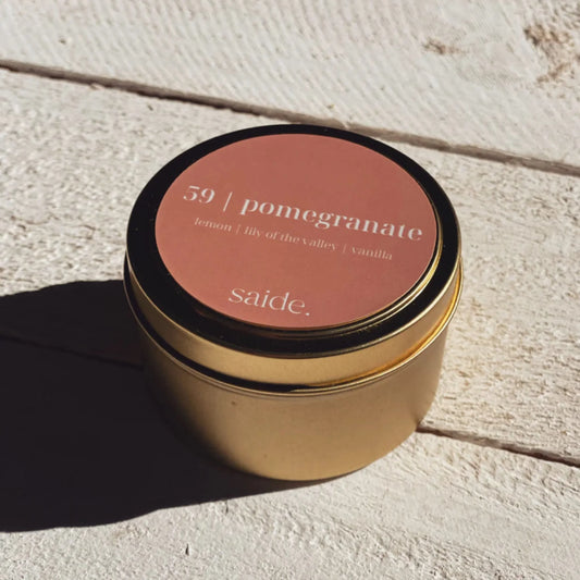 Gold candle jar with a pink lid on a light wooden surface
