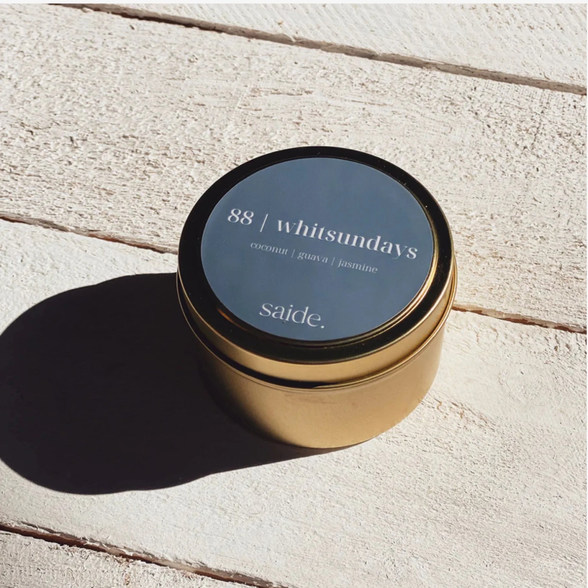 Gold candle jar with a blue label on a wooden surface
