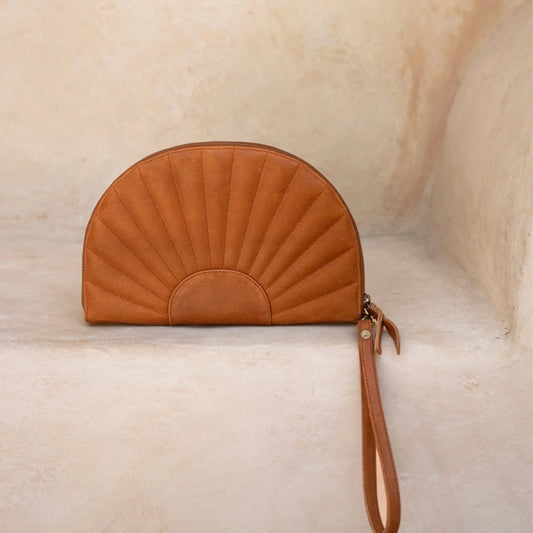 Brown leather clutch bag with a textured surface on a beige background