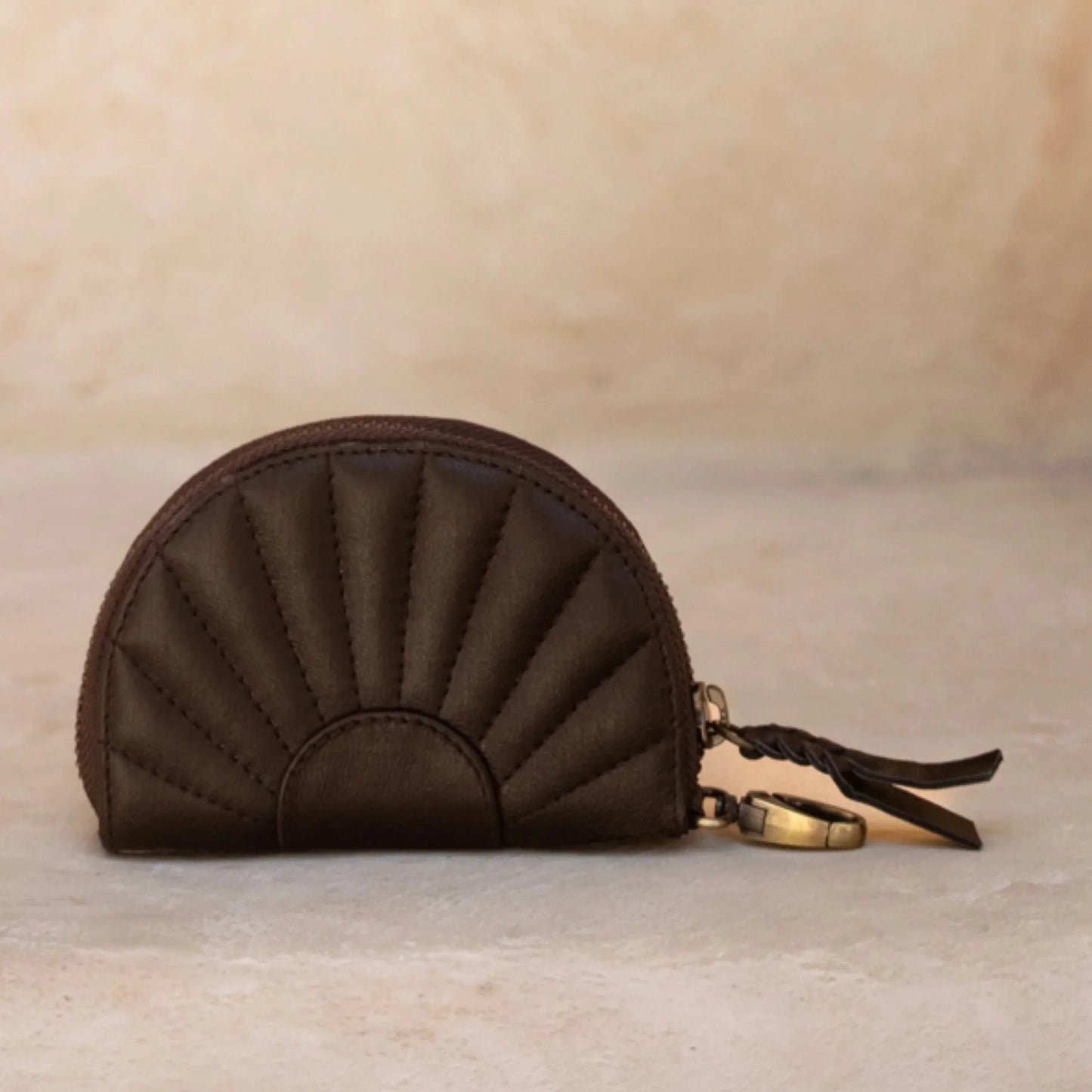 Brown quilted coin purse with a keychain on a beige background