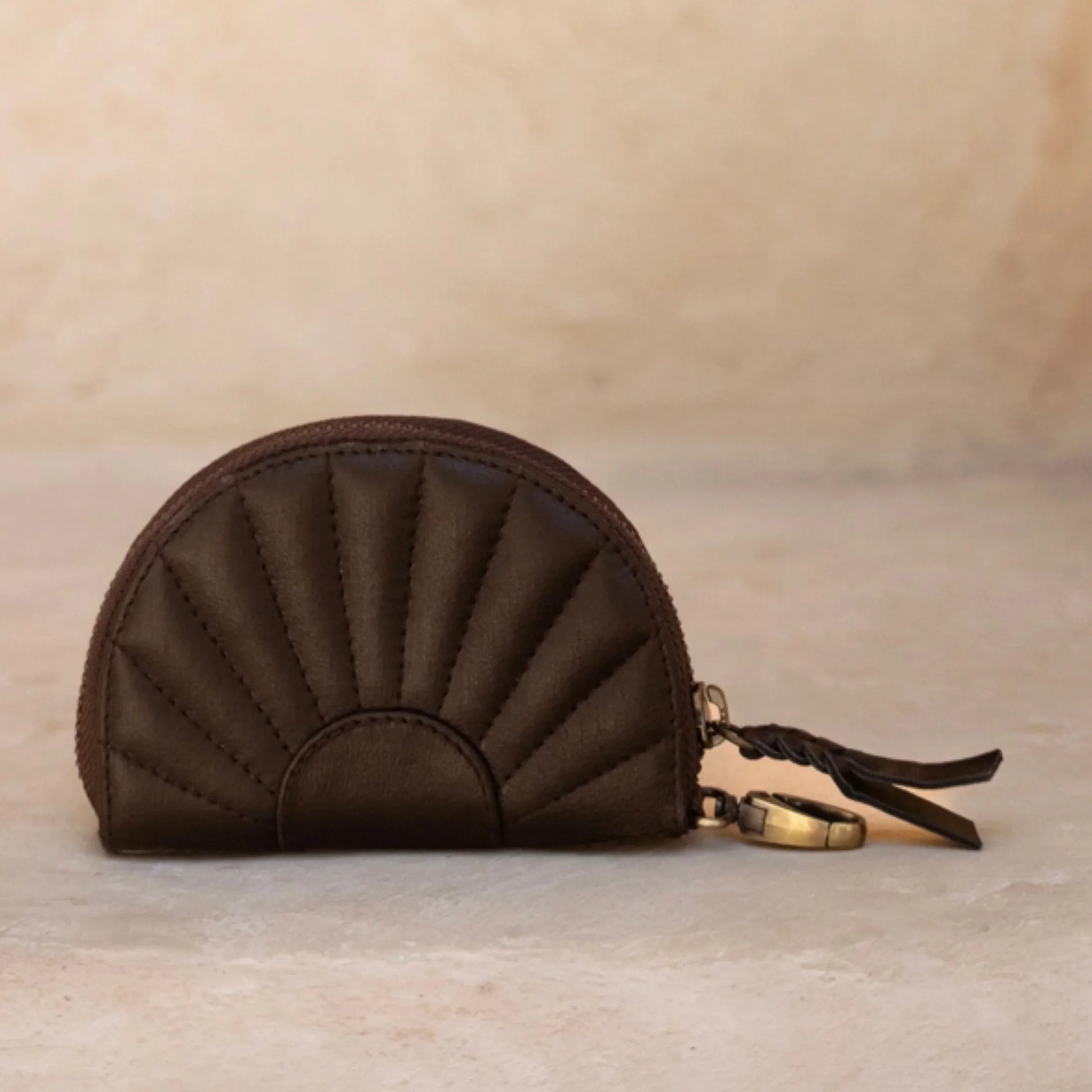 Brown quilted coin purse with a keychain on a beige background