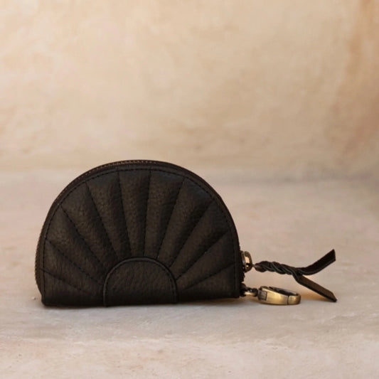 Black textured purse with a keychain on a beige background