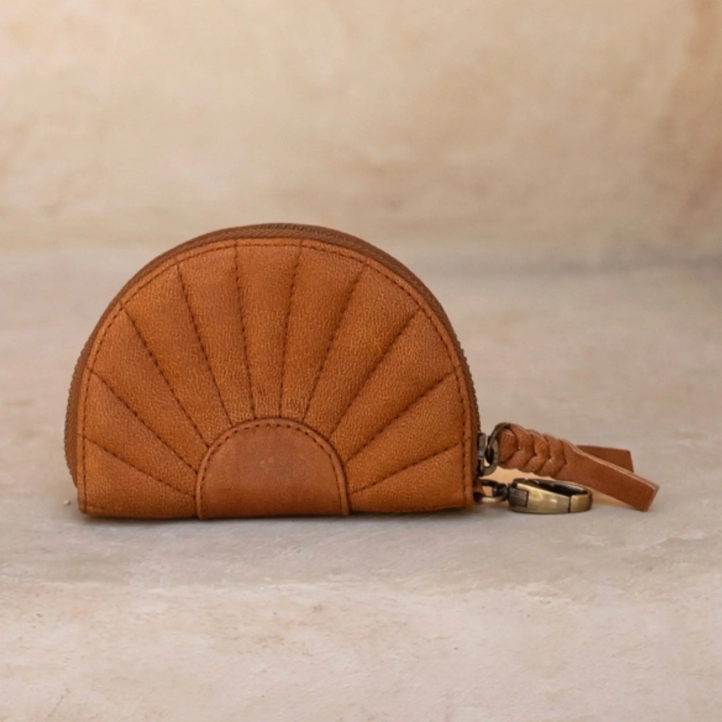 Chestnut brown quilted coin purse with a keychain on a beige background