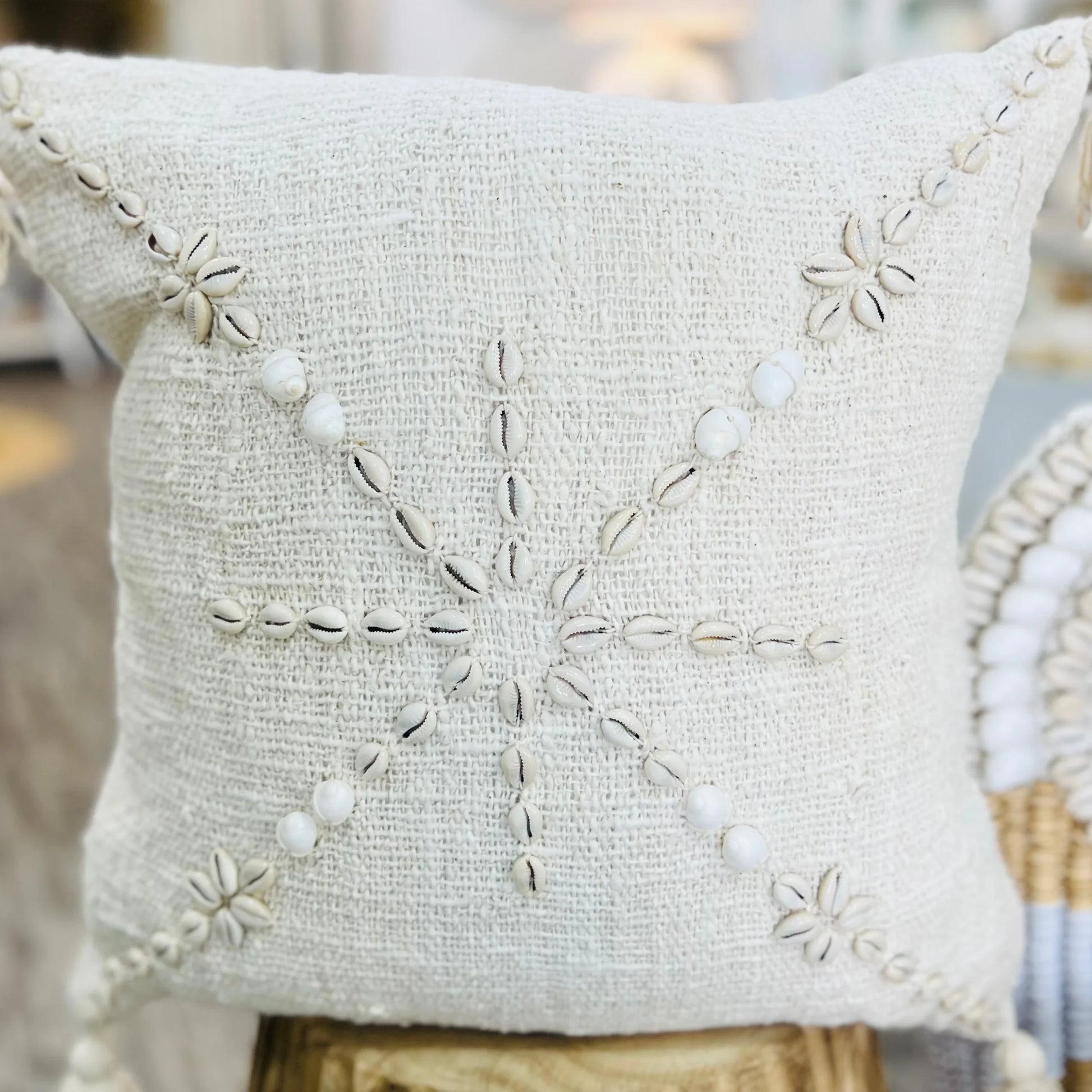 Decorative pillow with shell embellishments on a blurred background