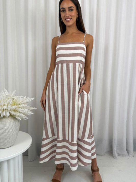 Woman wearing a brown and white striped dress standing in front of white curtains.