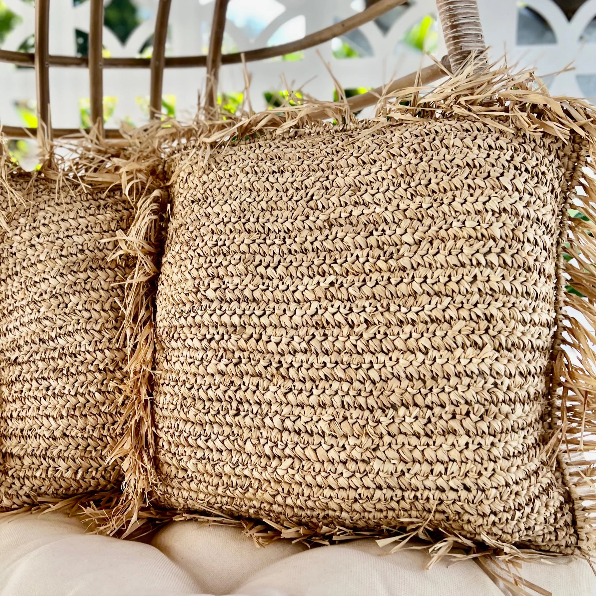 Close-up of woven straw cushions with fringes on a blurred background