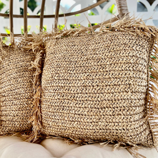 Close-up of woven straw cushions with fringes on a blurred background