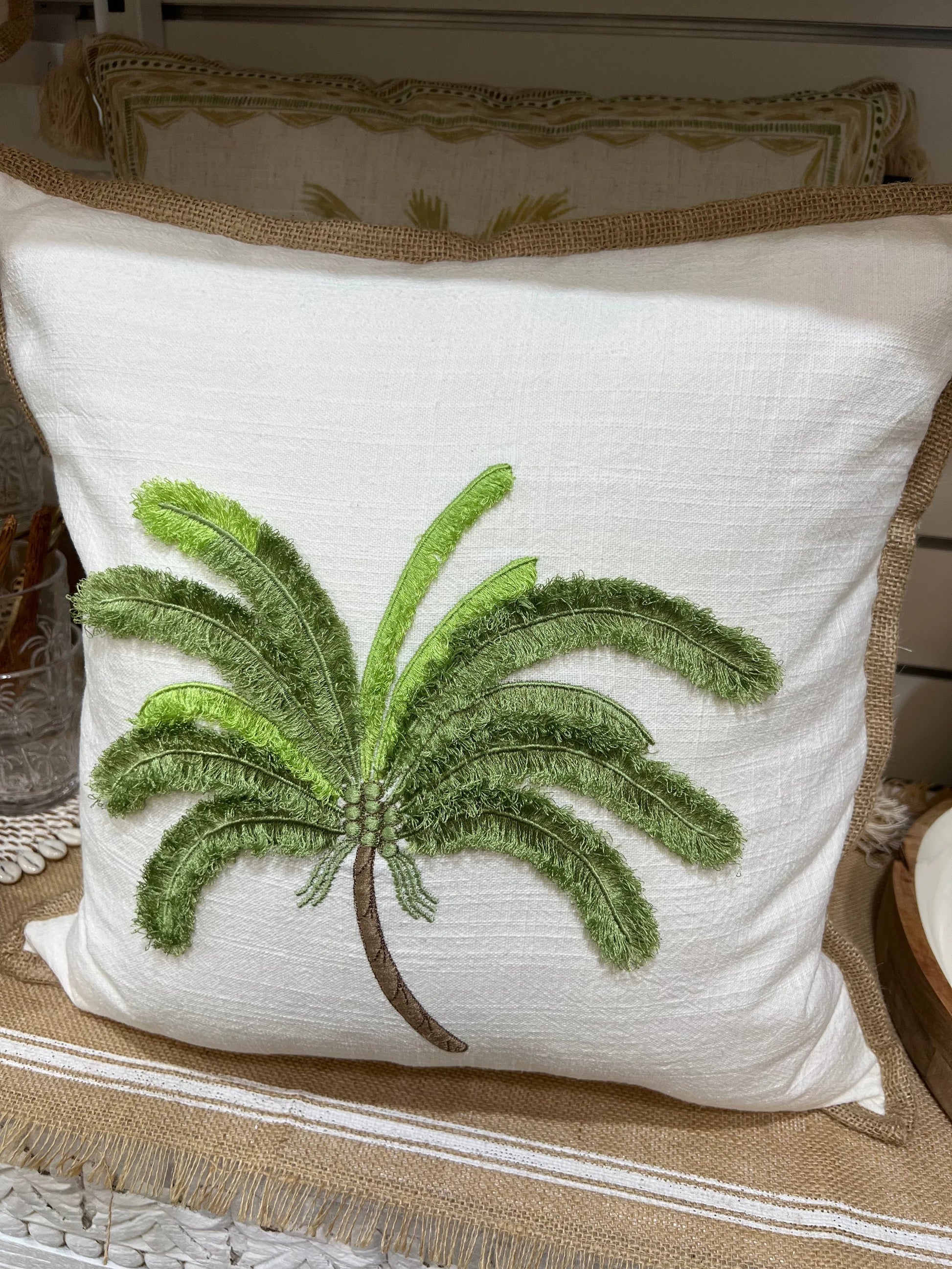 White pillow with green palm tree design on a textured surface